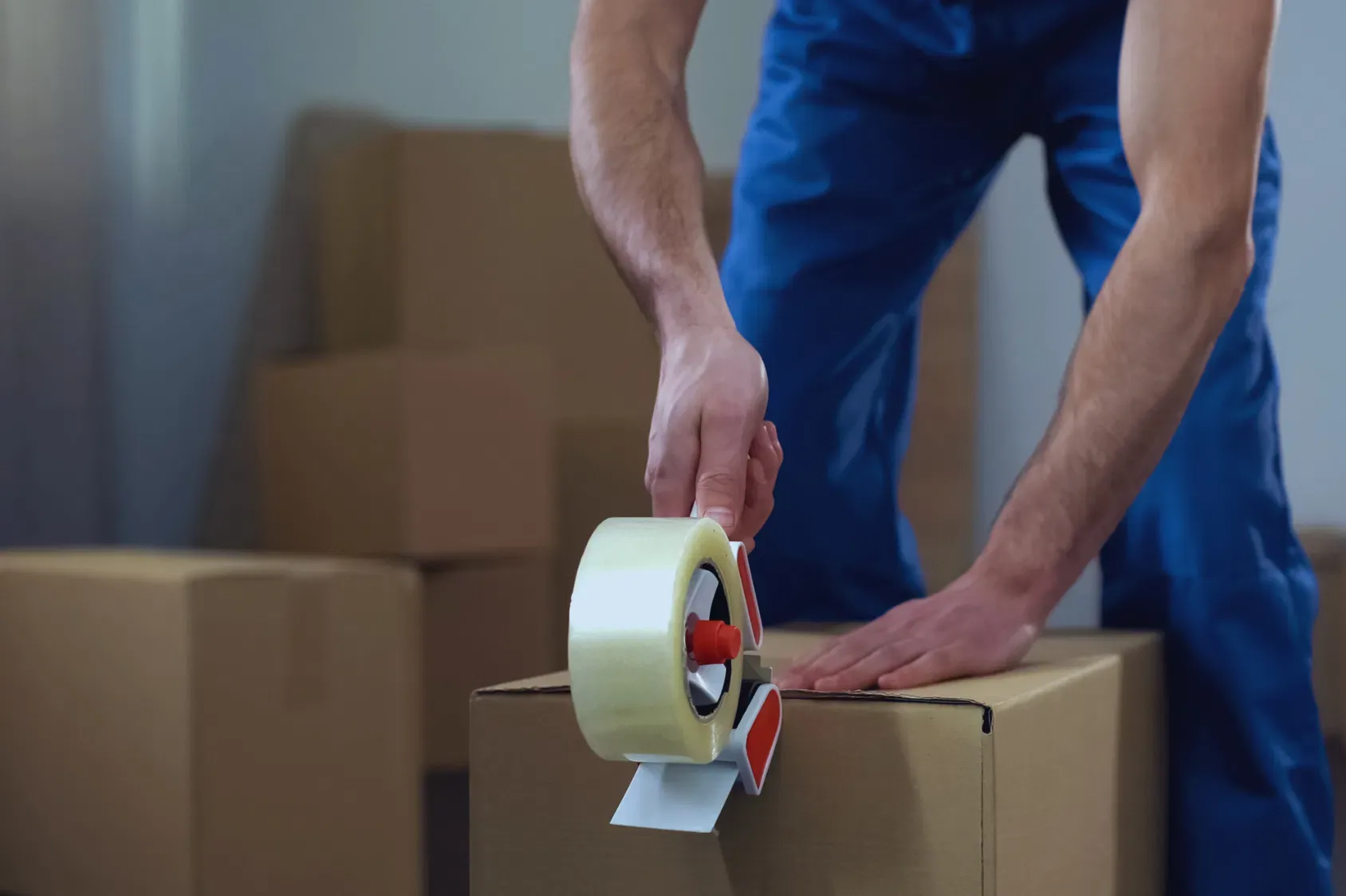 Mover sealing a cardboard box with packing tape